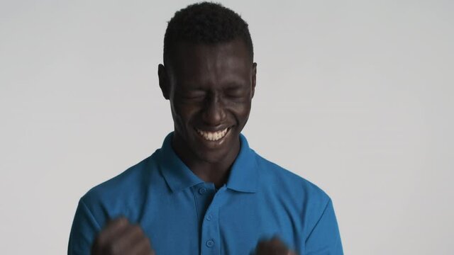 Young attractive African American man joyfully showing yes gesture on camera over gray background. Celebrating expression