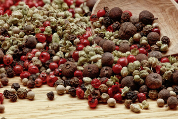 Assortment of scattered spices close-up on a wooden board. Various types of red, black pepper and dried thyme seeds.	