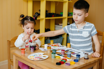 A boy and a girl play together and paint. Recreation and entertainment. Stay at home
