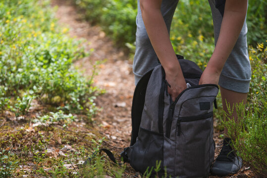 walking in the woods, woman taking a phone from bags side pocket
