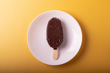 tasty cold chocolate ice cream with nuts pieces on wooden stick