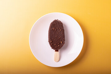 tasty cold chocolate ice cream with nuts pieces on wooden stick