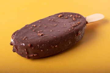 tasty cold chocolate ice cream with nuts pieces on wooden stick