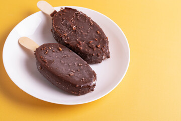 tasty cold chocolate ice cream with nuts pieces on wooden stick