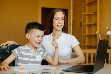 A mother and her child are engaged in distance learning at home in front of the computer. Stay at...