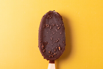 tasty cold chocolate ice cream with nuts pieces on wooden stick