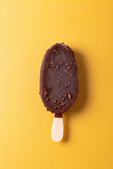 tasty cold chocolate ice cream with nuts pieces on wooden stick