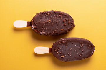 tasty cold chocolate ice cream with nuts pieces on wooden stick