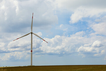 Fototapeta premium Modern wind turbine in field on cloudy day. Alternative energy source