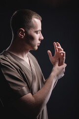 Portrait of a strong and large male masseur in special clothes with a finger at the temple reads...