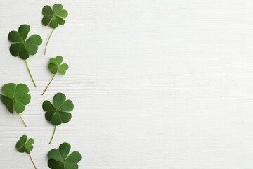 Clover leaves on white wooden table, flat lay with space for text. St. Patrick's Day symbol - obrazy, fototapety, plakaty