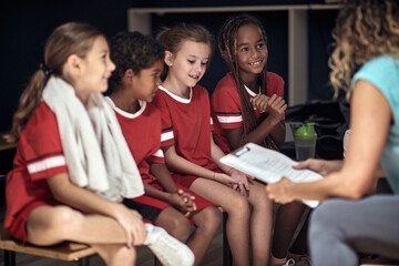 Coach discussing with kids players in changing room.