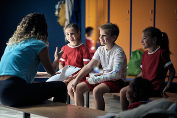 boy with broken arm wrapped medical cast plaster in locker room  talking with  coach.