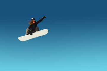 Fototapeta na wymiar Girl snowboarder in flight after jumping amid blue sky gradient blank designer winter snowboarding sport