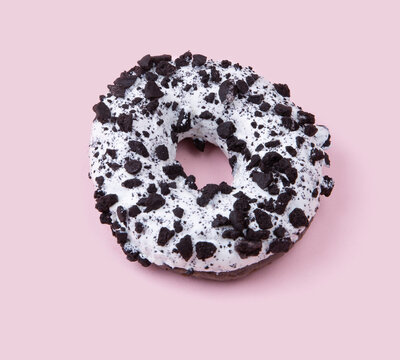  donut in dark chocolate glaze with pieces of chocolate on a pink background. High quality photo