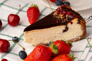 Piece of cheesecake with chocolate top and berries