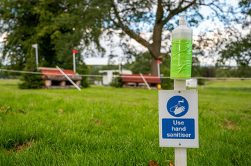 Hand sanitiser and Covid-19 reminder sign at an outdoor horse trials event