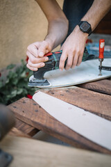Male hands polishing board with power sander. Portrait of man's hands using power sander on wooden board.