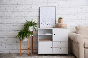 Modern white cabinet near brick wall in room. Interior design
