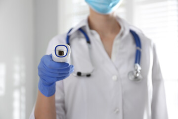 Doctor holding non contact infrared thermometer indoors, focus on hand. Measuring temperature