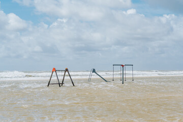 Spielplatz und Spielgräte wie Schaukel und Rutsche stehen bei Flut im Wasser. Keine Menschen