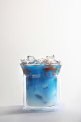Blue matcha tea with milk and coffee in a glass Cup. soft drink. Light background. Copy of the space. Vertical photo.