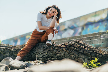 selective focus of cheerful woman sitting on tree trunk