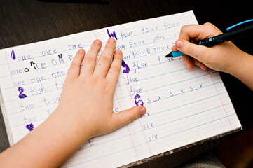 Child doing homework. School task, hand writing exercise. Learning to write number names.