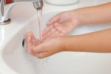 Manos de niño bajo el grifo con agua