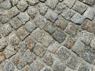 Close-up old paving stones. Cobbled street in Lviv, Ukraine. Old broken paved street. Pavement of stones. Granite cobblestones on pavement. Stone cement tile curving texture street.