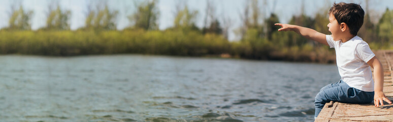 website header of emotional boy pointing with finger while sitting near river