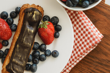Eclair cake with chocolate glaze on wooden tray