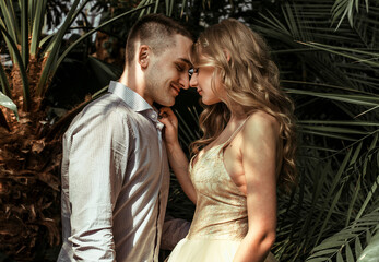 young couple posing in a botanical garden. wedding photo session with tropical plants.