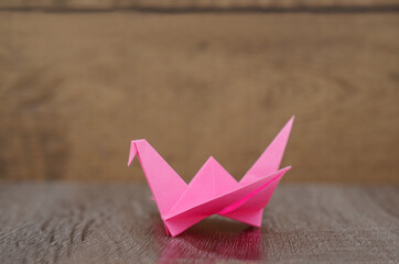Fototapeta na wymiar origami pink bird paper on wooden