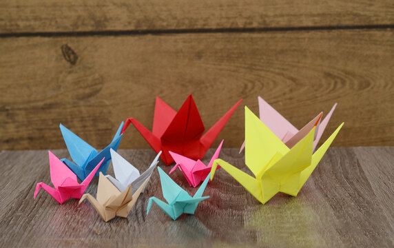 Group of colorful origami paper cranes on wooden