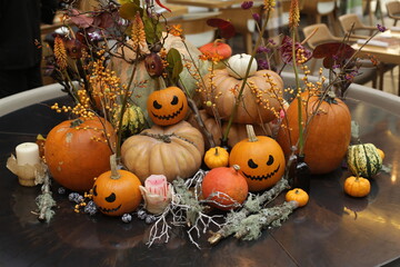Interior decoration with decorative autumn pumpkins for Halloween holiday. Fall still life with plants, pumpkins. Holiday decor. Horror. Halloween jack-o'-lanterns. Halloween mood, party. October 31
