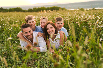Happy family on daisy field at the sunset having great time together