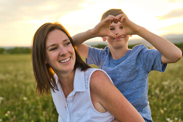 happy family of mother and child on field at the sunset having fun