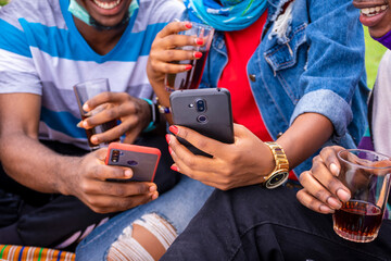 young african friends having drinks and using their mobile phones