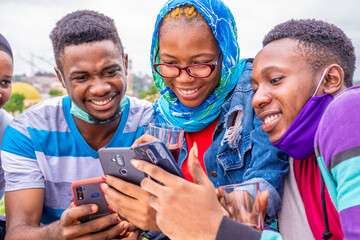 young african friends having drinks, using their phone