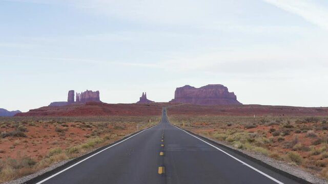 Slow motion shot of famous empty road leading to sandstone buttes of Monument Valley Navajo Tribal Park on the Arizona-Utah border in USA
