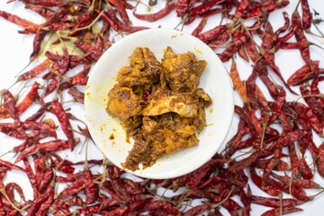 Mangsho Kosha or Chicken Curry in a Plate with Blurred Red Chilies Background with Selective Focus