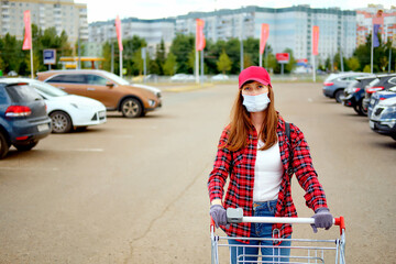 girl with a shopping cart. The buyer is in quarantine. Buyer wearing a mask and gloves.