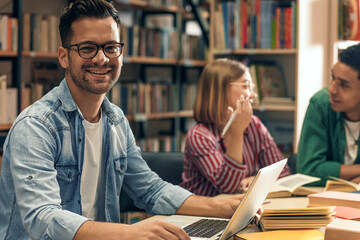 Young male student study in the library using laptop for researching online.