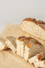 Loaf of homemade bread with sliced bread from wheat and seeds on parchment paper