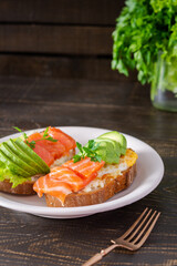 Different delicious sandwiches for breakfast, bread with cheese, avocado and trout, sandwich with egg and parsley