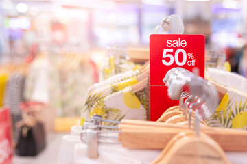 Red sale sign 50% discount on clothing rack in modern shopping mall or department store with copy space. Retail shop promotional event, new product discount, or business marketing advertising concept