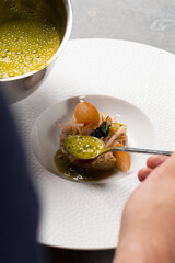 Chef cuisinier verse sauce sur plat gastronomique à base de fruits de mer