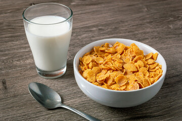 Bowl with healthy cornflakes and milk on light table