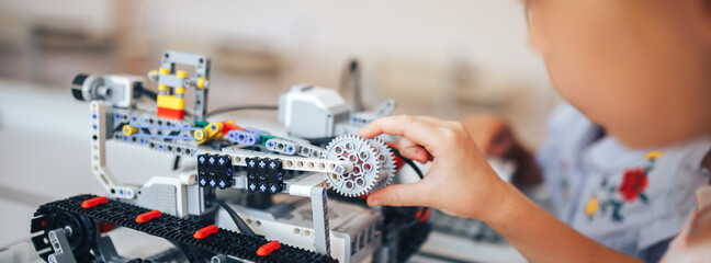 Two schoolgirls study in a robotics class, assemble a robot constructor